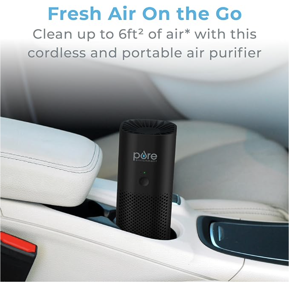 Portable air purifier by Pure Enrichment, shown in a car cup holder, emphasizing its compact and travel-friendly design. The device is lightweight, featuring a black cylindrical shape with a power button and branding.