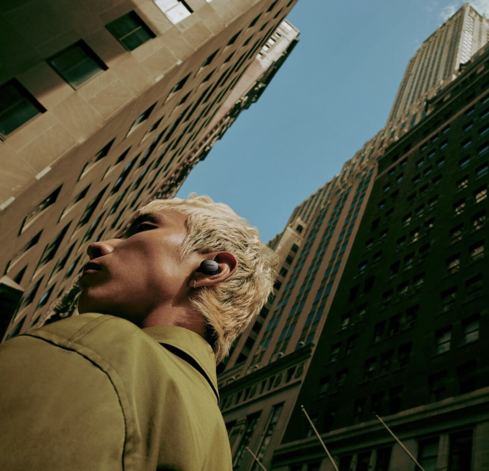 Person wearing Bose QuietComfort Earbuds in the city, showcasing sleek and stylish design