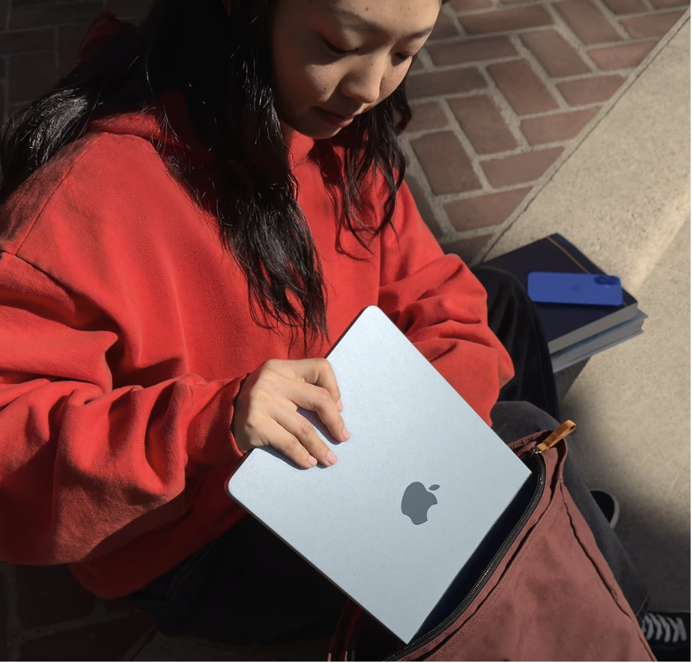 Student pulling out a 2025 MacBook Air in Sky Blue from a backpack outdoors