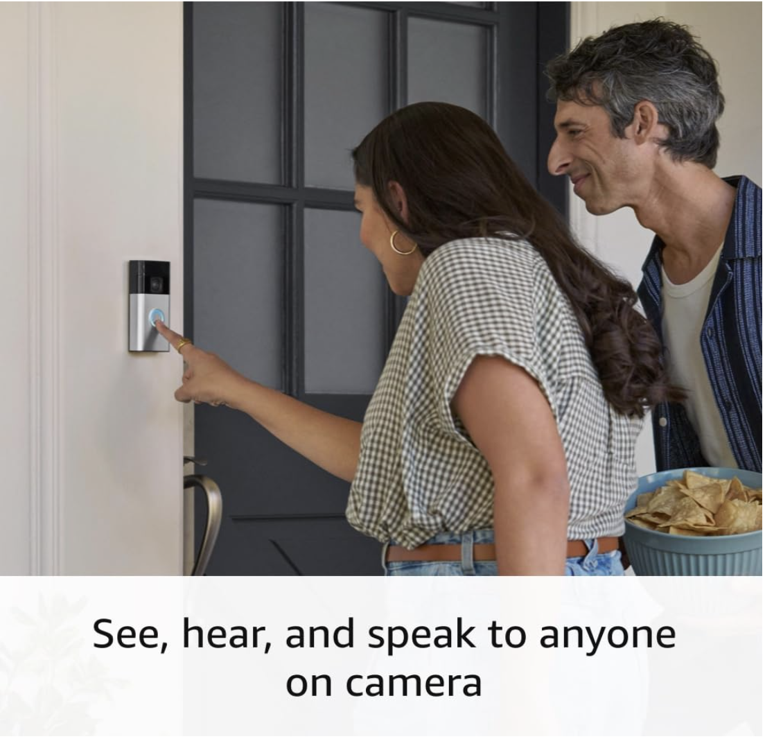 Woman presses the Ring Battery Doorbell Plus while a man stands beside her holding a bowl, showing two-way communication at the front door.