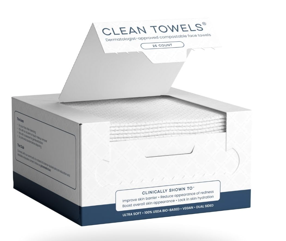 Open box of Clean Skin Club Clean Towels™ showing stack of dermatologist-approved, 100% biobased disposable face towels (25 count) for hygienic skincare use.