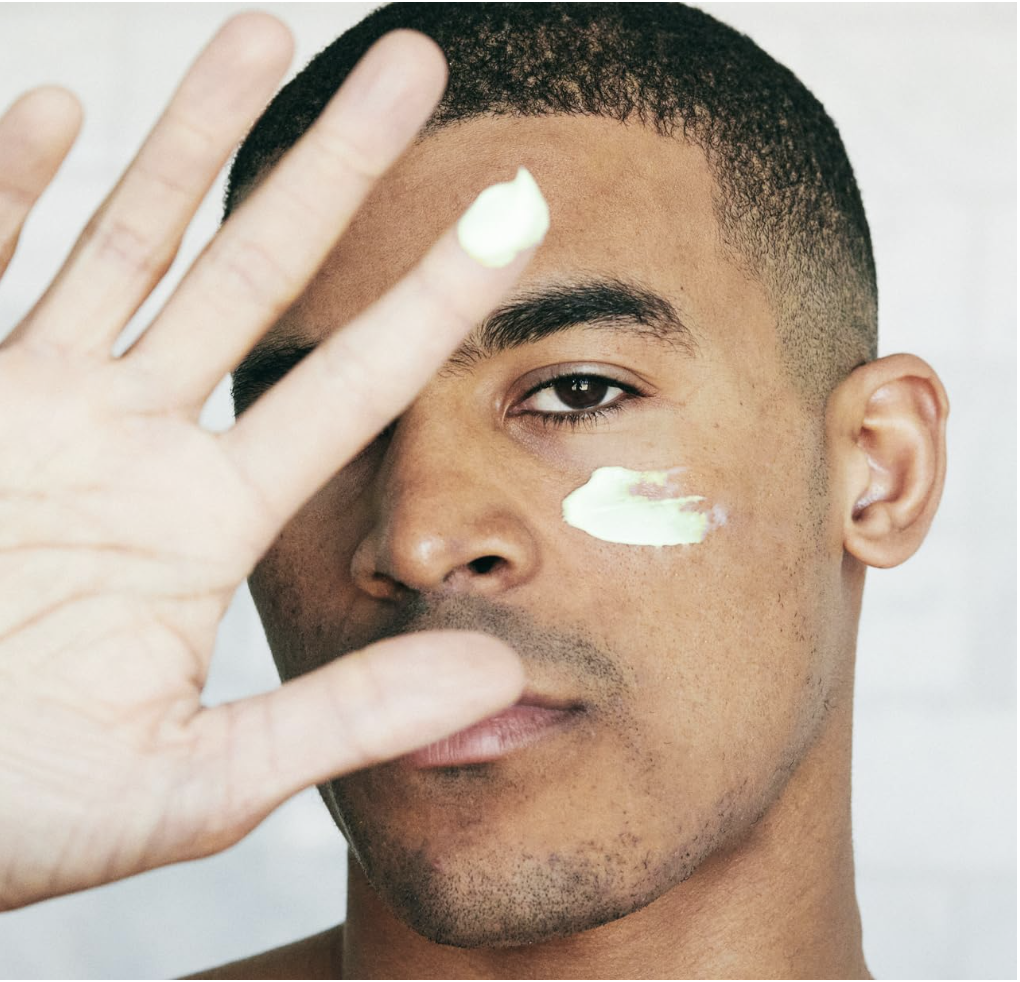 Man applying Brickell Men’s Retinol Face Moisturizer Cream with visible cream on cheek.