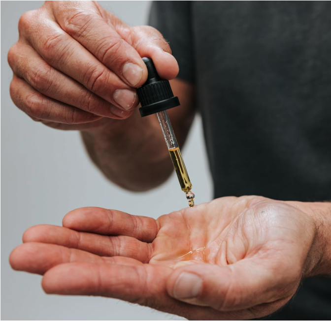 Man applying Caldera + Lab The Good serum with dropper into palm before evening skincare routine