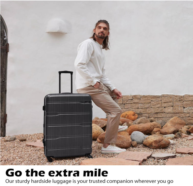 Man standing with Coolife luggage 28-inch expandable suitcase in charcoal finish, outdoor travel scene.