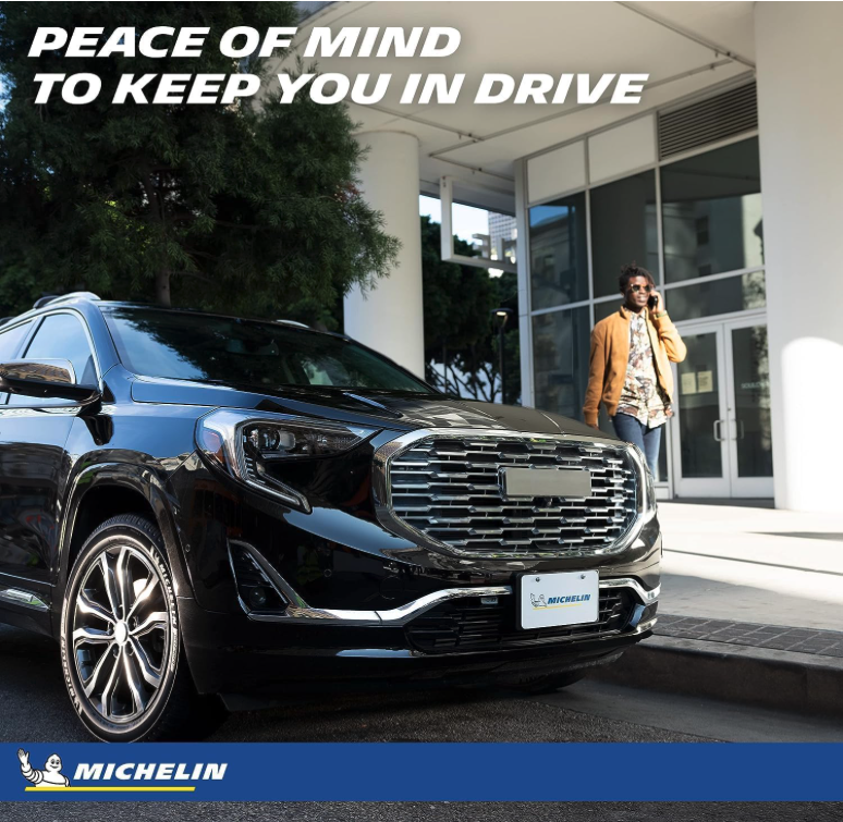 Crossover driving along a curved highway with Michelin Defender2 tires and city skyline in background